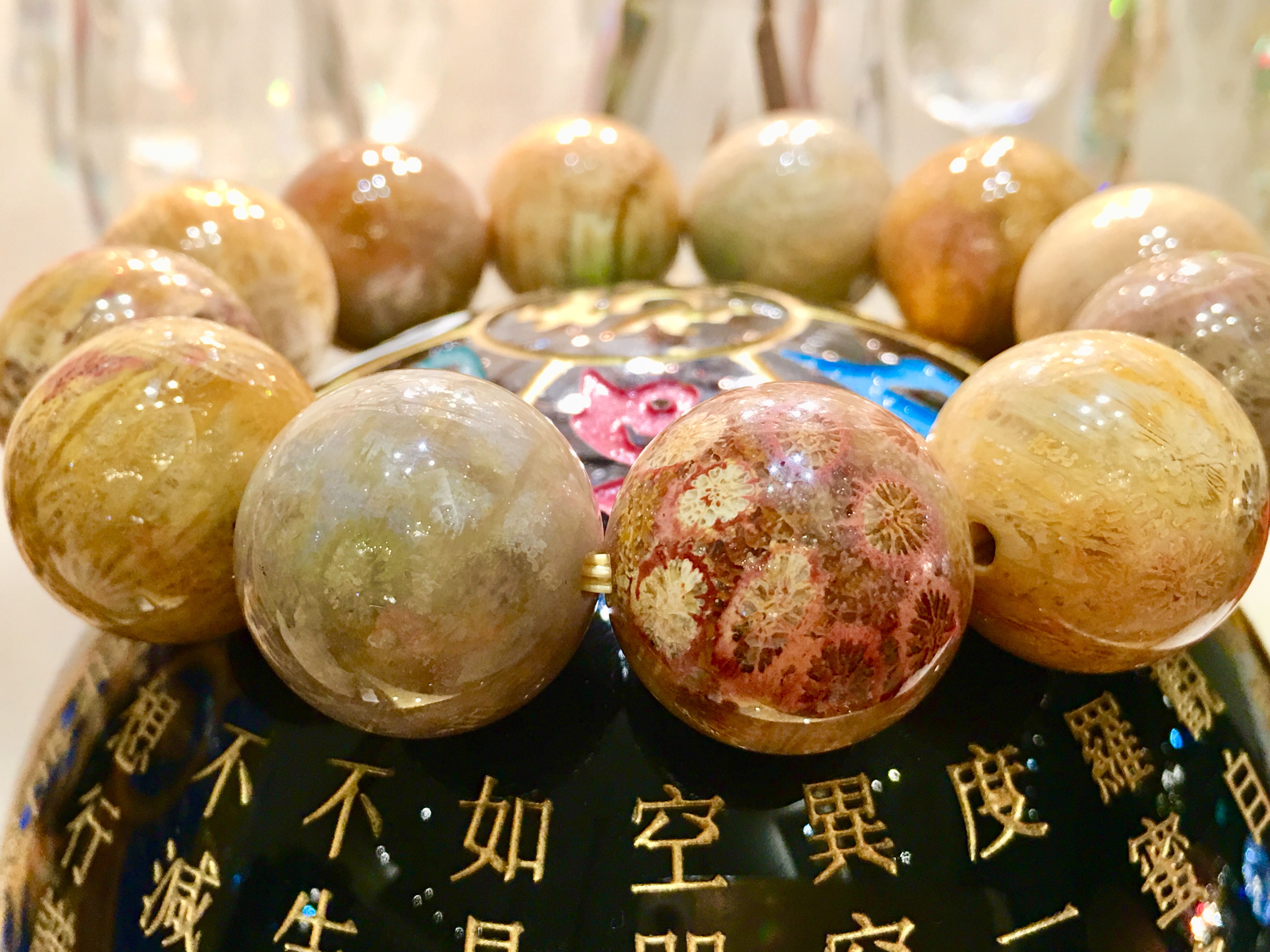 一排金黃與粉橘色的珊瑚玉圓珠，下方是刻有文字的底座