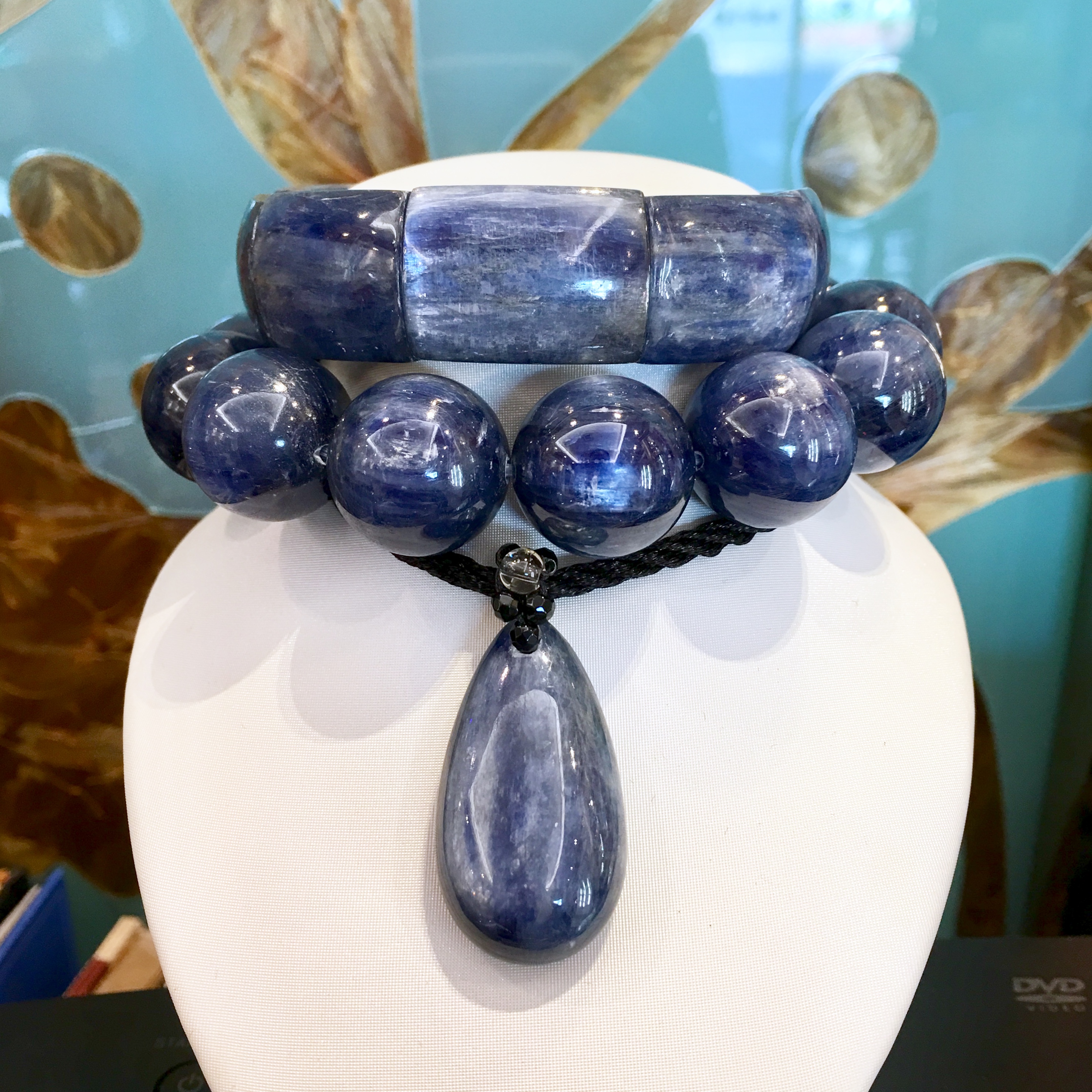 深藍色藍晶石手串與水滴墜，掛在白色展示架上